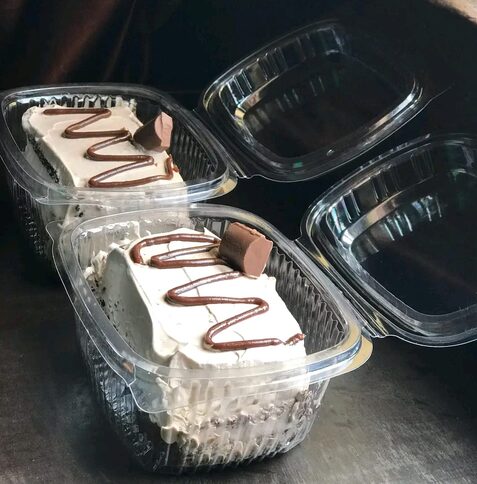 Dessert cups with cream and chocolate drizzle in takeaway boxes