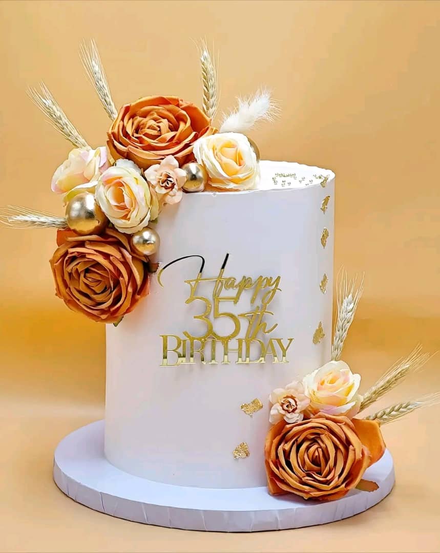 White birthday cake with terracotta roses and gold detailing by Unique Bakery